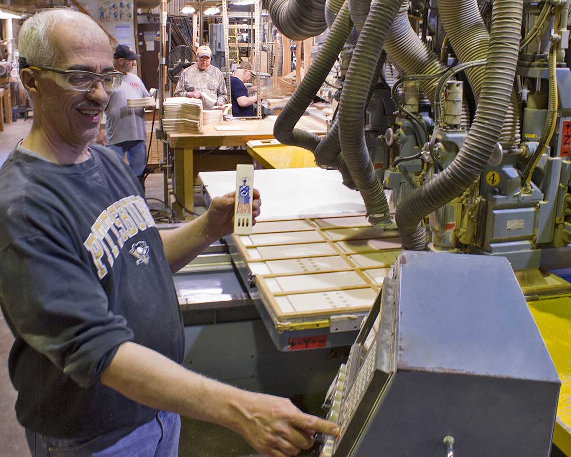 A worker enters settings into a machine which makes wooden train whistles at Channel Craft's Pennsylvania plant